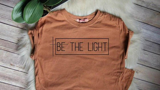 Women's brown shirt with quote Be The Light.