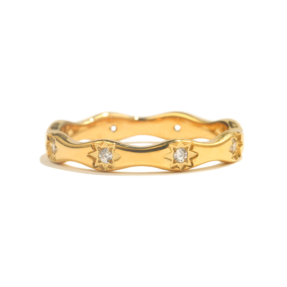 Gold ring with starburst and CZ details on white background.