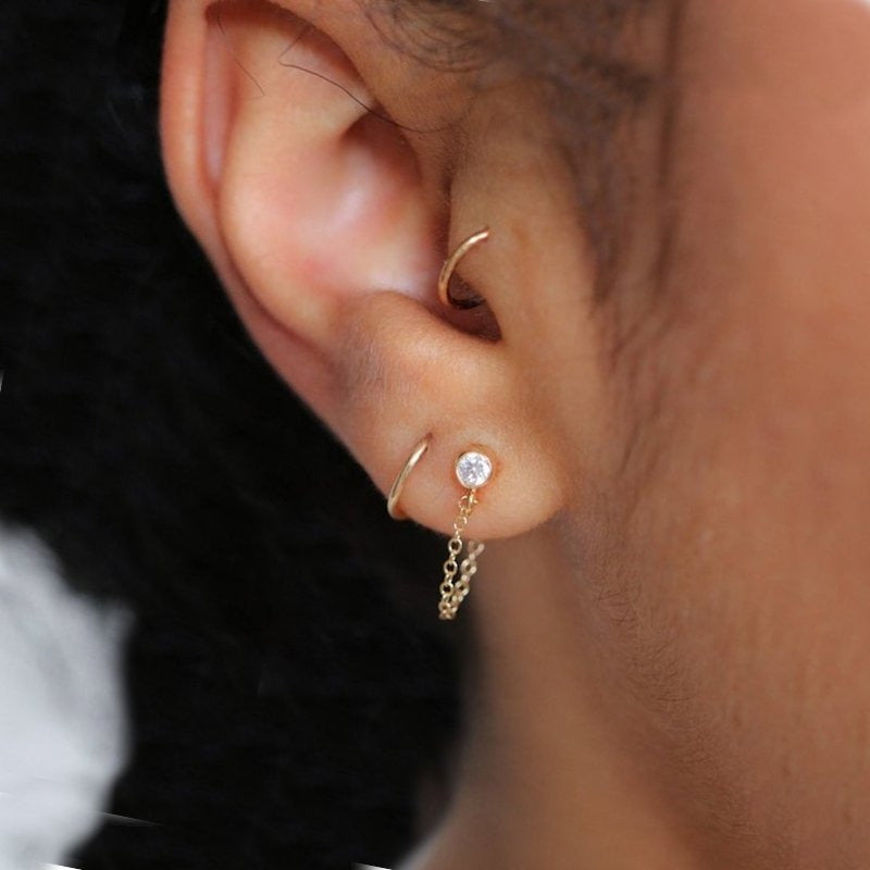A woman wearing a gold chain drop earring.