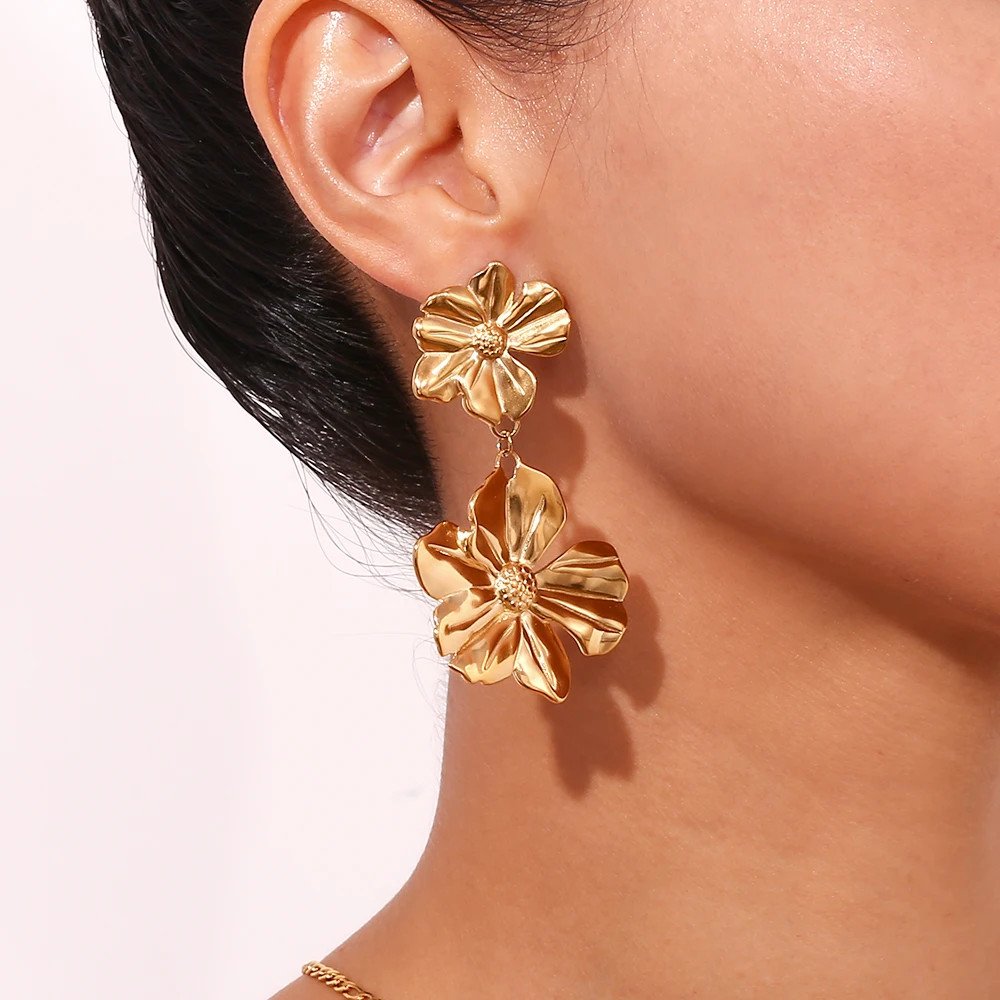 A woman wearing Gold Flower Drop Earrings.