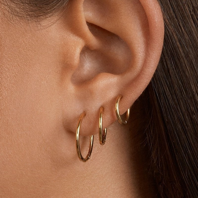 A model wearing three gold hoop earrings.