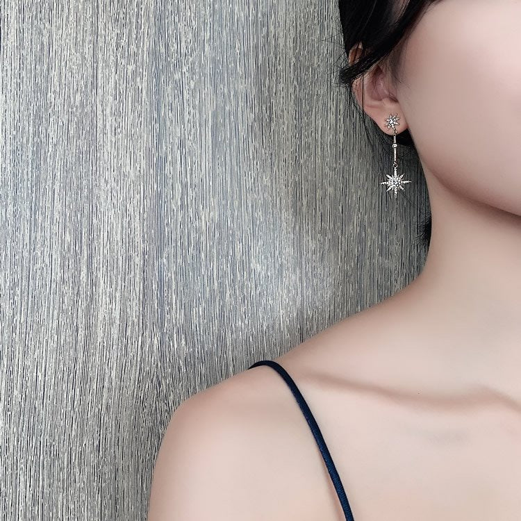 A model wearing the Sparkling Star Gold Dangle Earrings.