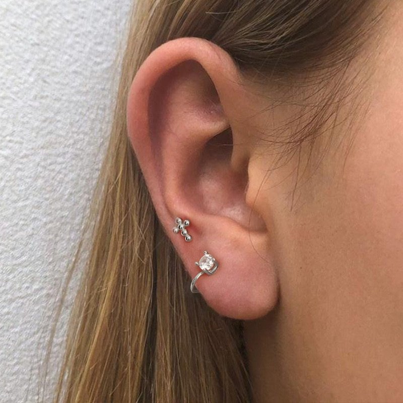 A woman wearing a silver tiny cross stud.