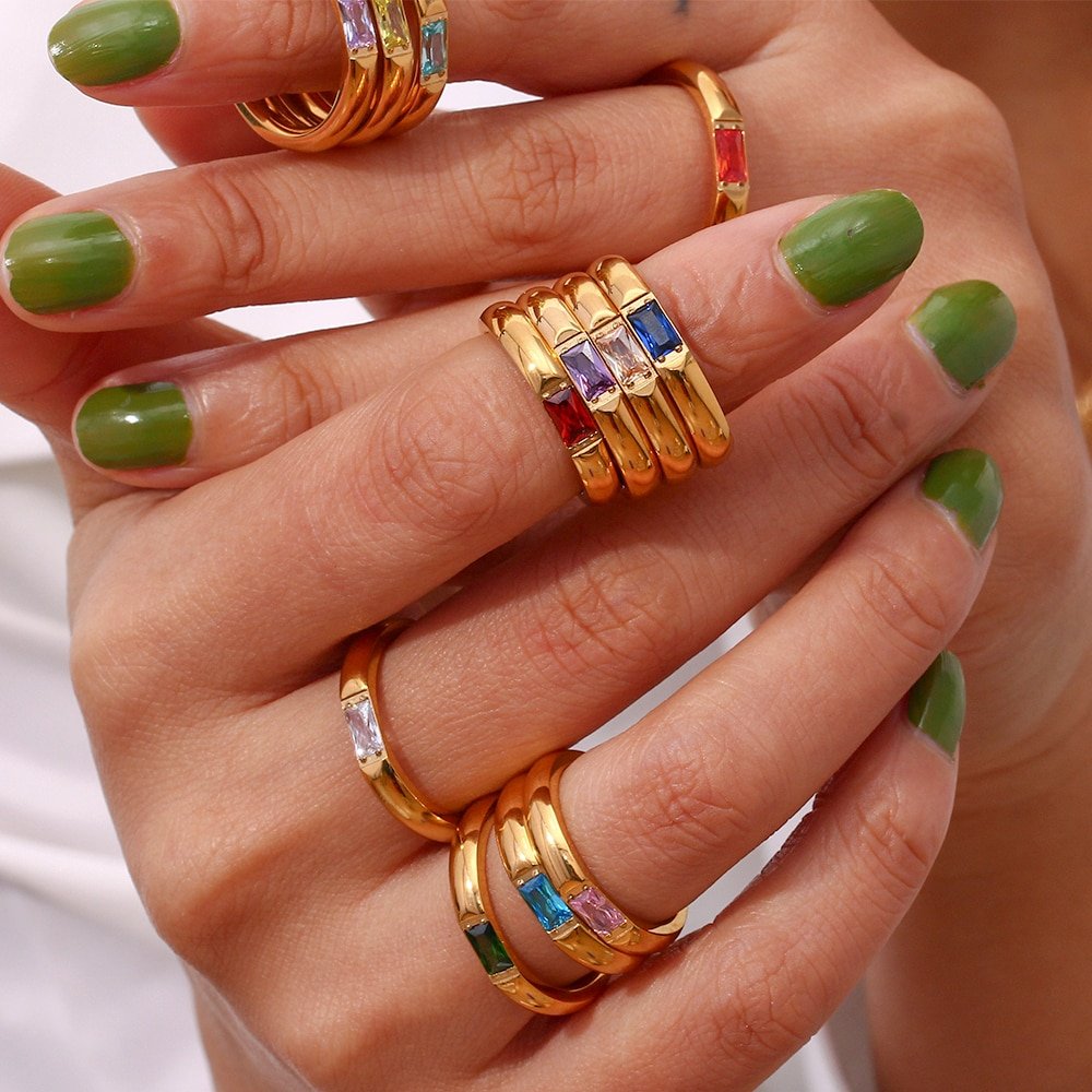 A model wearing multiple gold birthstone rings.