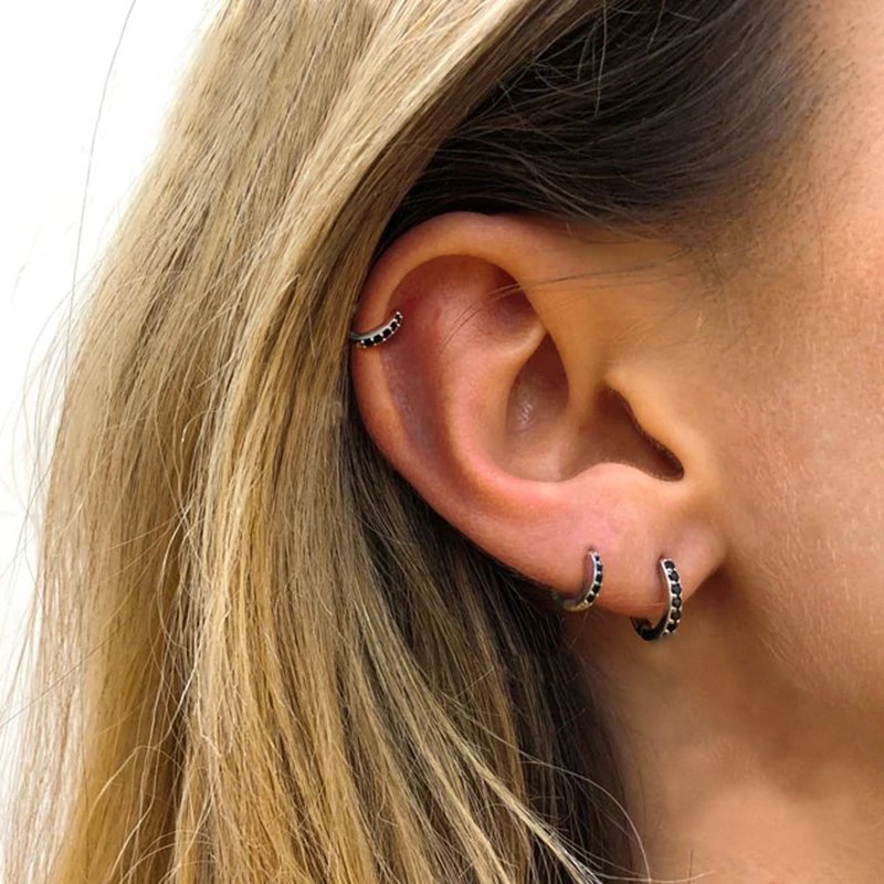 A woman modeling the black zircon huggies in silver.