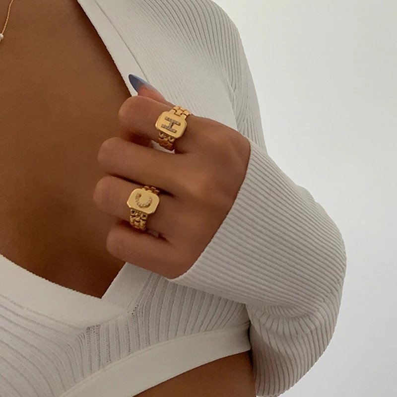 A model wearing two chunky gold initial rings.