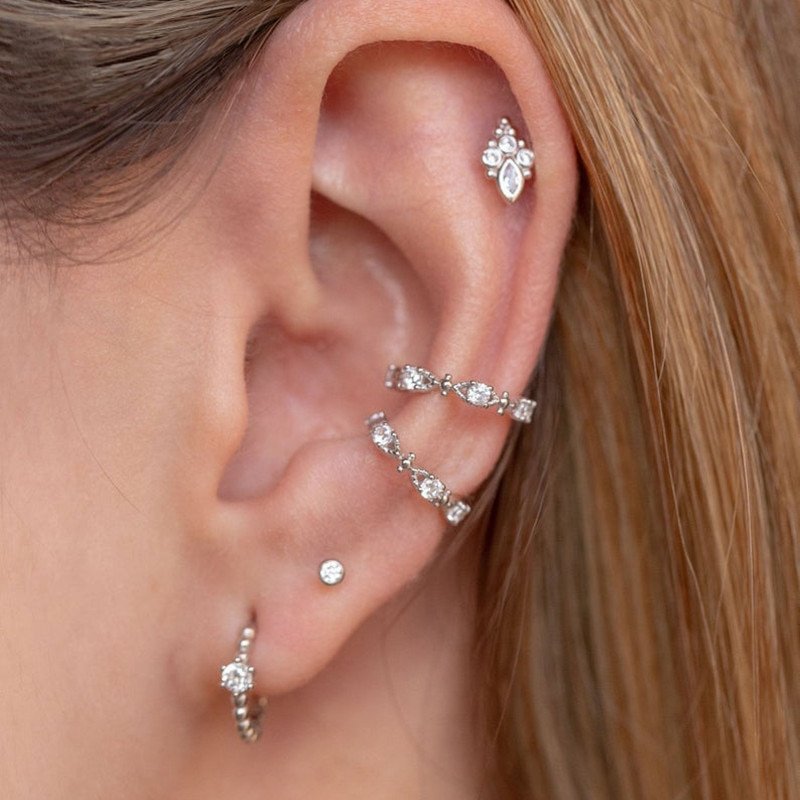 A model wearing multiple silver studs and ear cuffs with clear CZ stones.