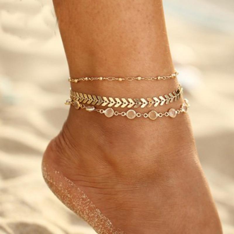 A model wearing a gold triple anklet set.