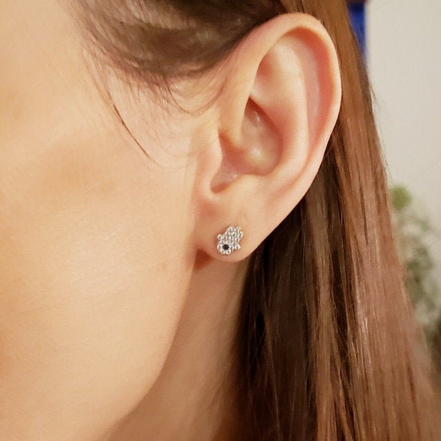 A model wearing the silver Hamsa Hand Studs.