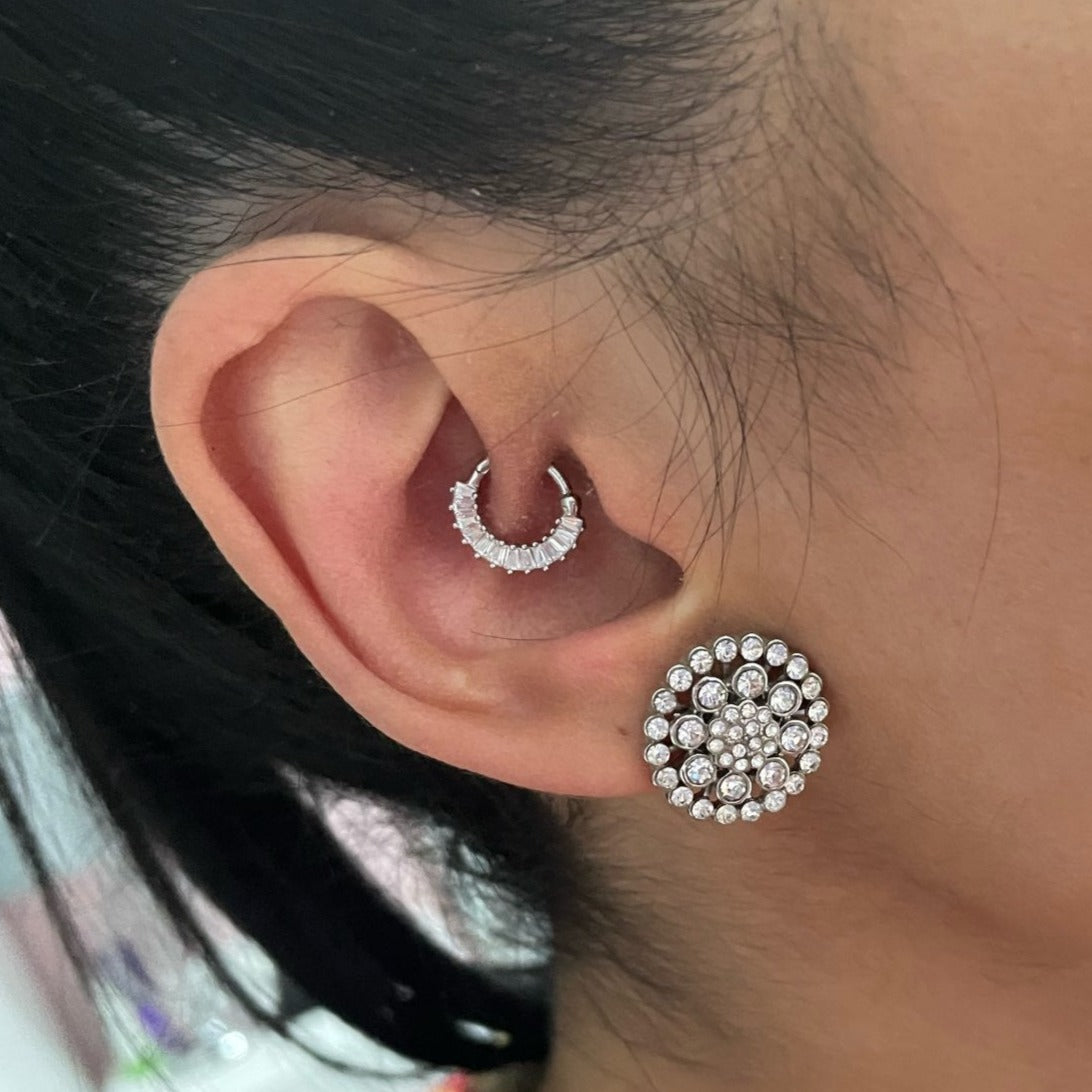 A woman wearing sparkly silver statement earrings.