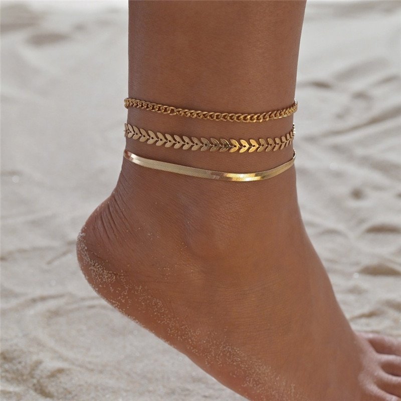 A woman wearing multiple anklets on the beach.