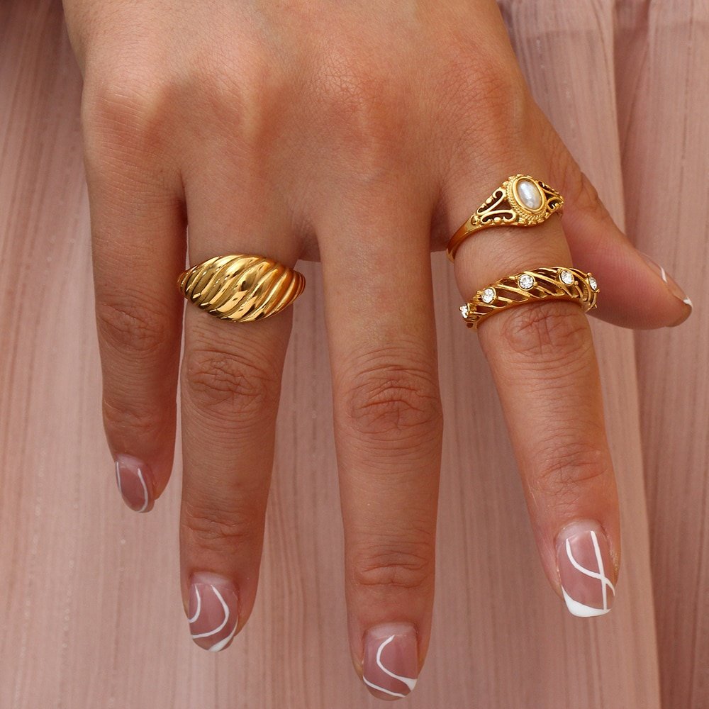 A woman wearing multiple gold statement rings.