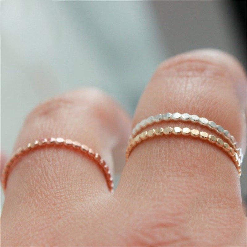 A model wearing gold, rose gold and silver flat beaded stacking rings.