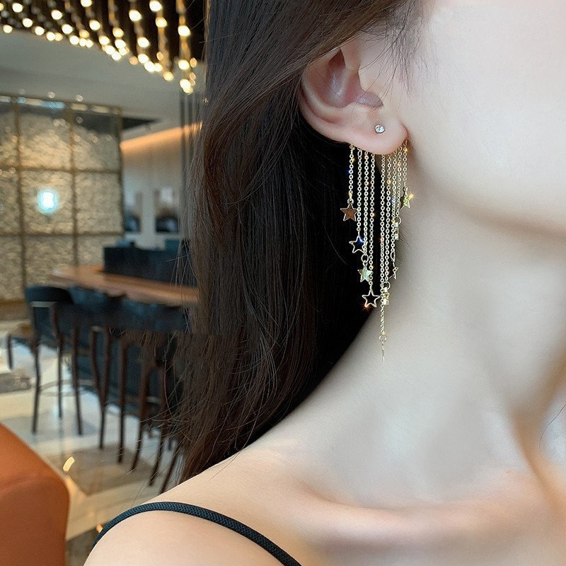 A model wearing gold star statement earrings.