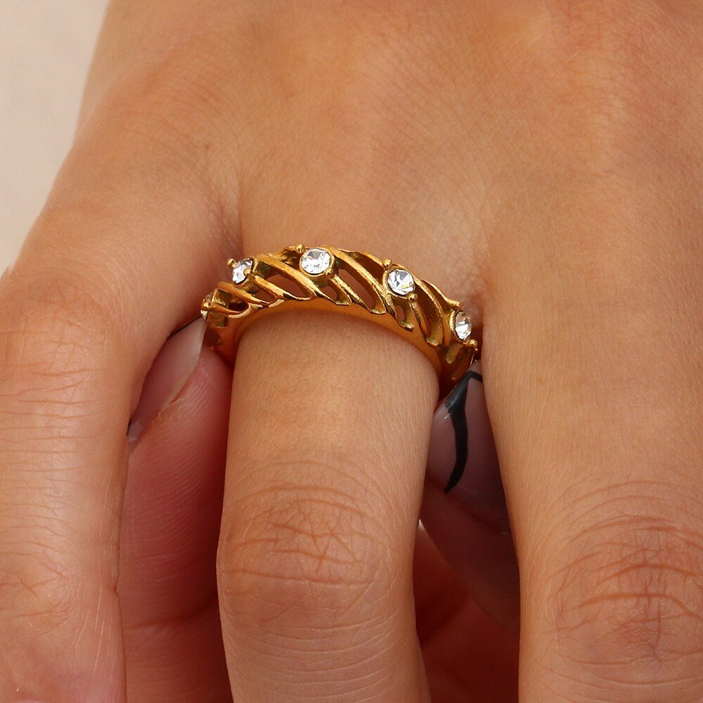 A model wearing a gold hollow cage ring with CZ stones.