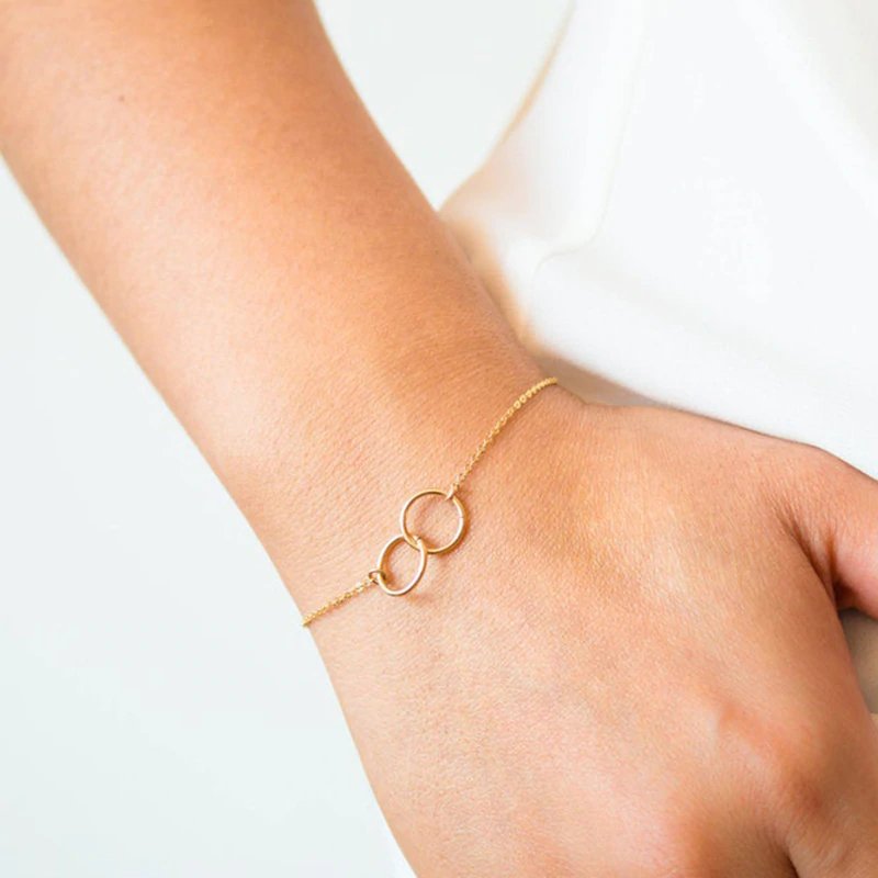 A model wearing a delicate gold braclet with interlocking circles.