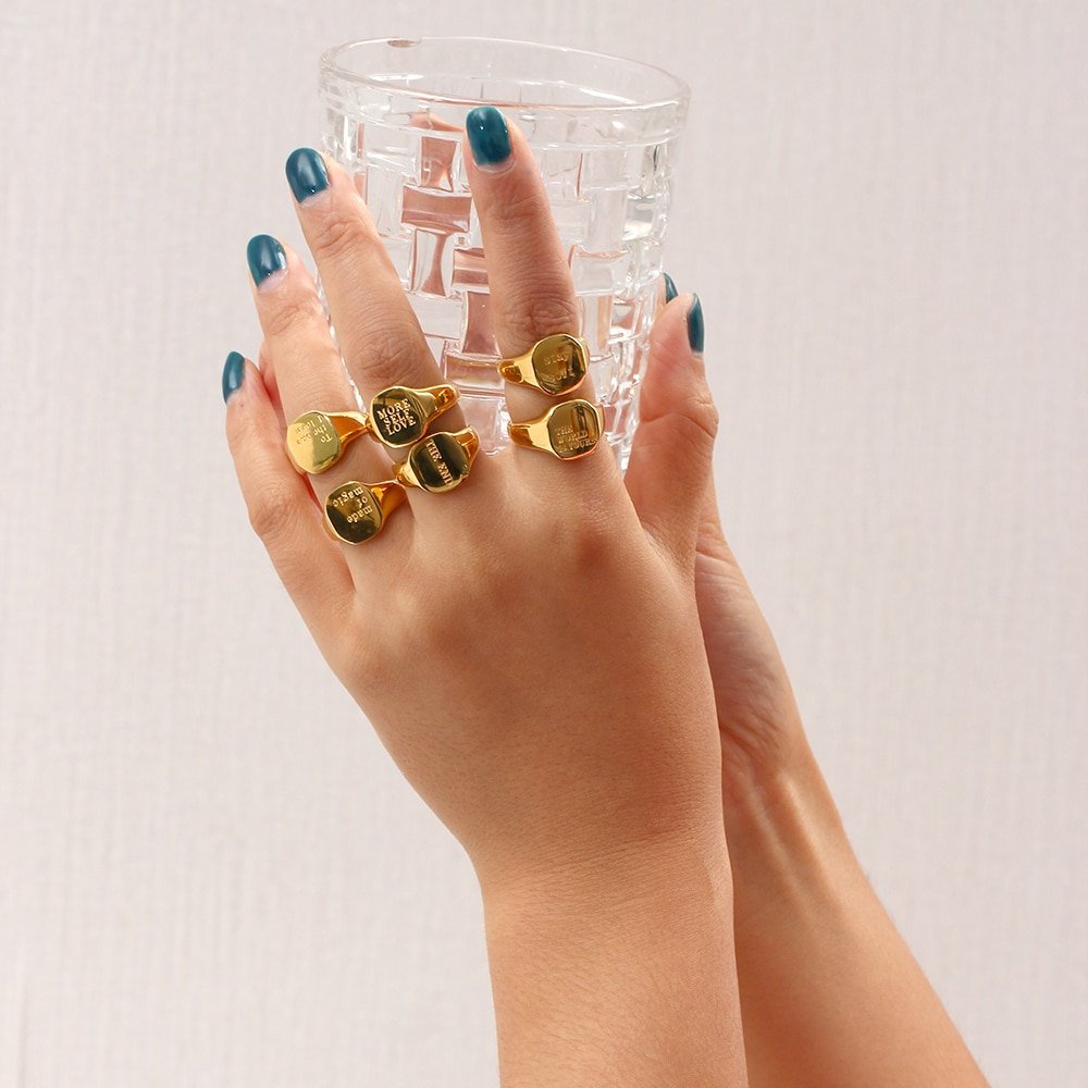 A model wearing six gold Positive Message Signet Rings.