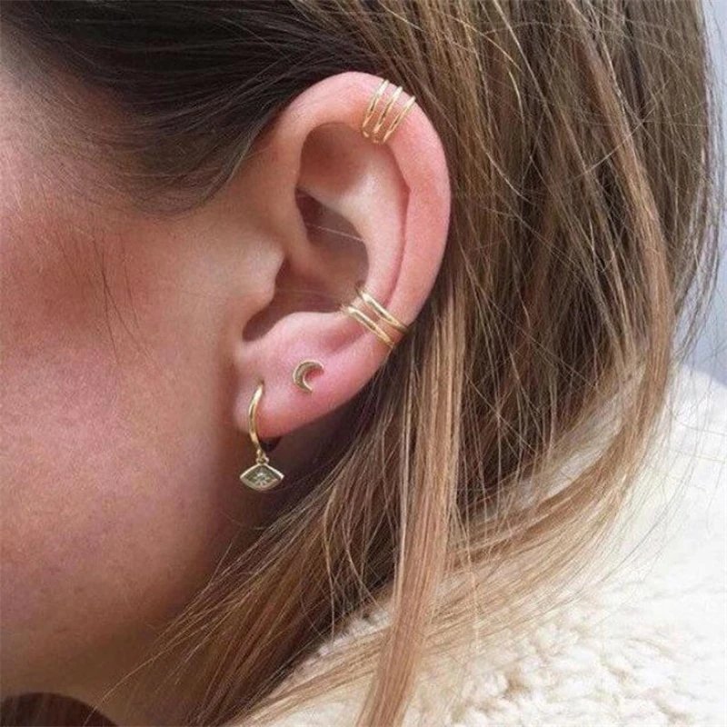 A woman wearing gold ear cuffs.