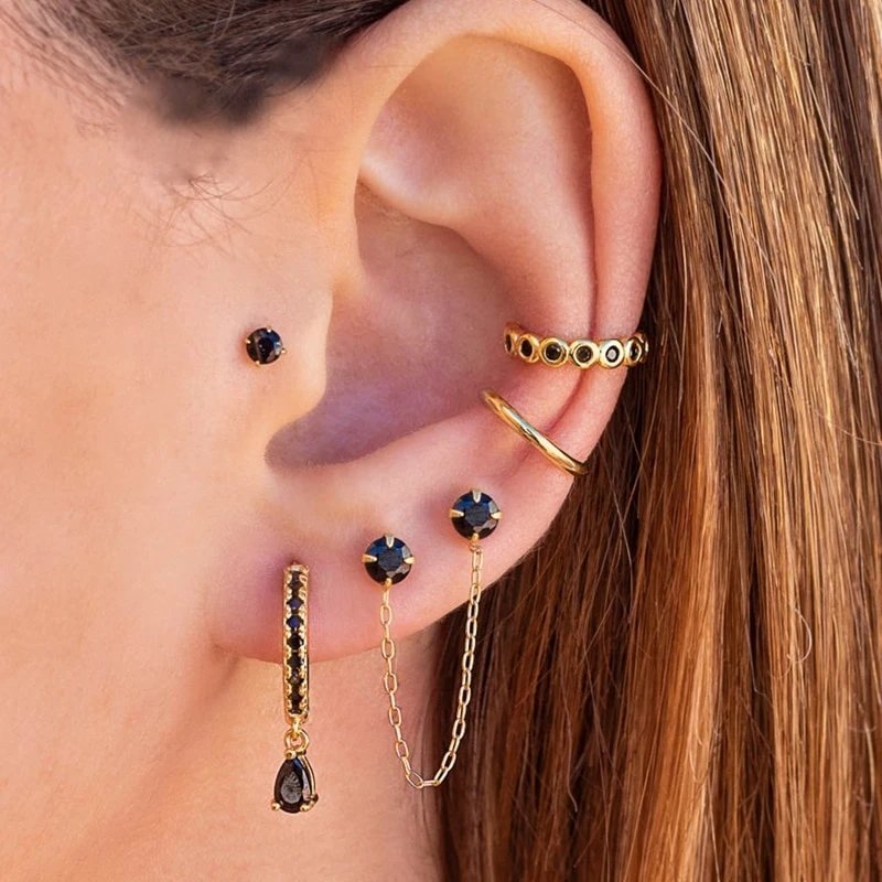 A woman wearing multiple gold piercings with black zircon stones.