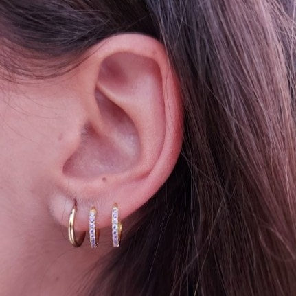 A model wearing the Simple Huggie Hoops with Classic Pave Huggies.