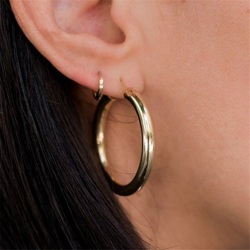 A model wearing the Simple Huggie Hoops with a larger hoop.