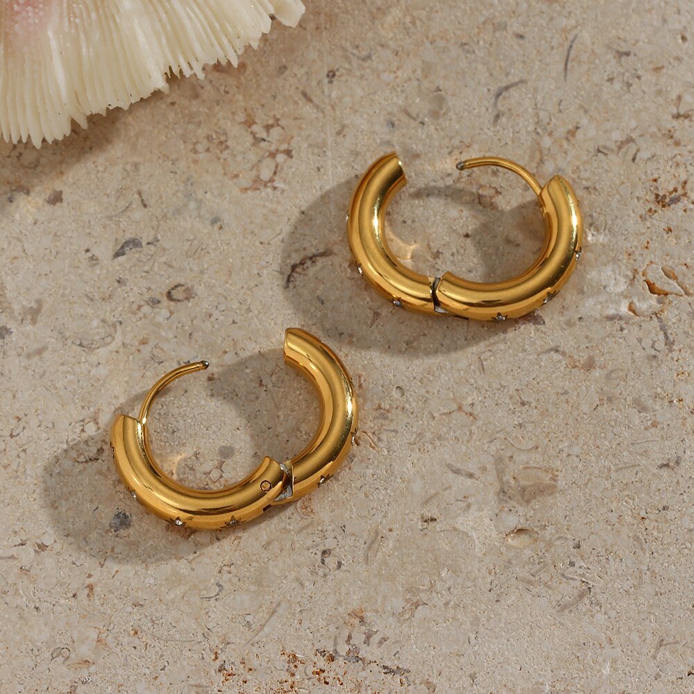 Gold hoops sitting with the hinge open.