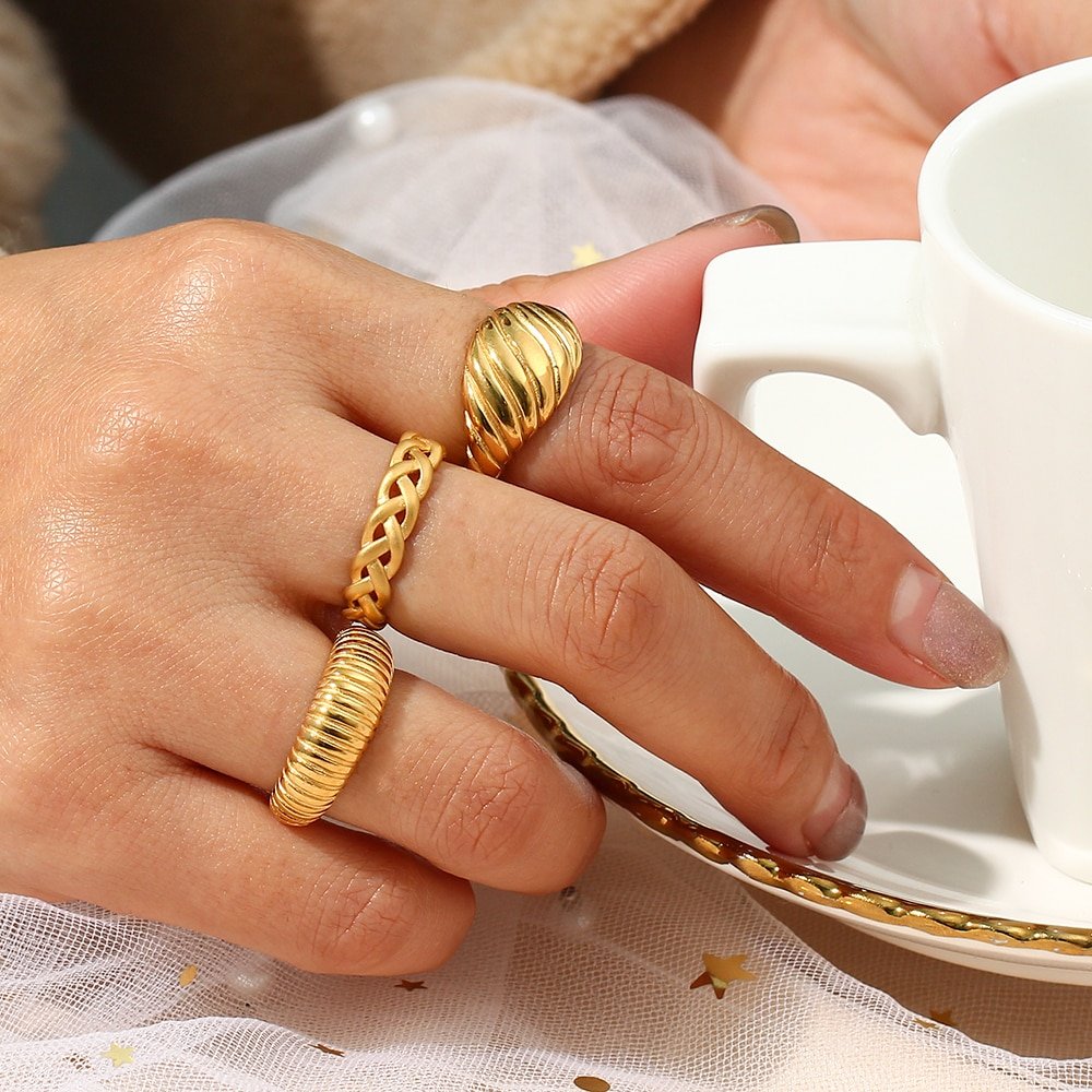 A woman wearing chunky gold rings.