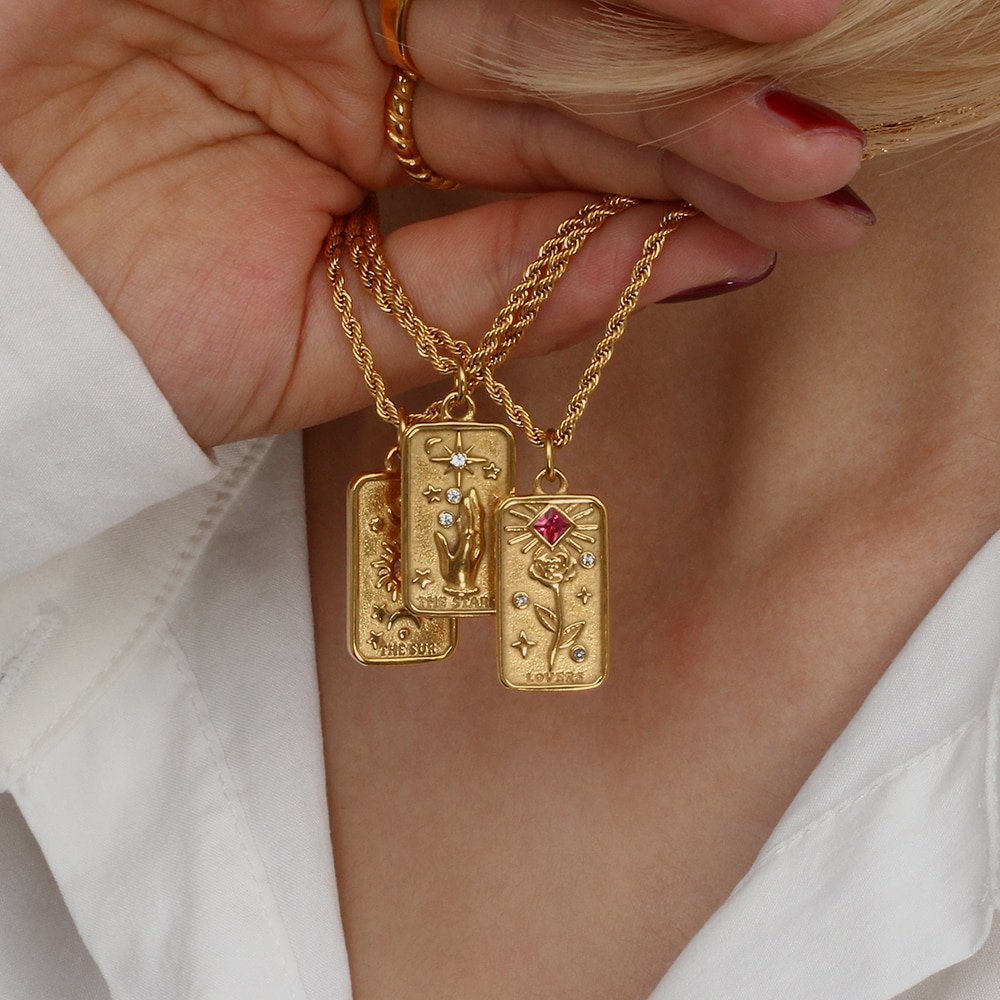 A model wearing three gold tarot card necklaces.