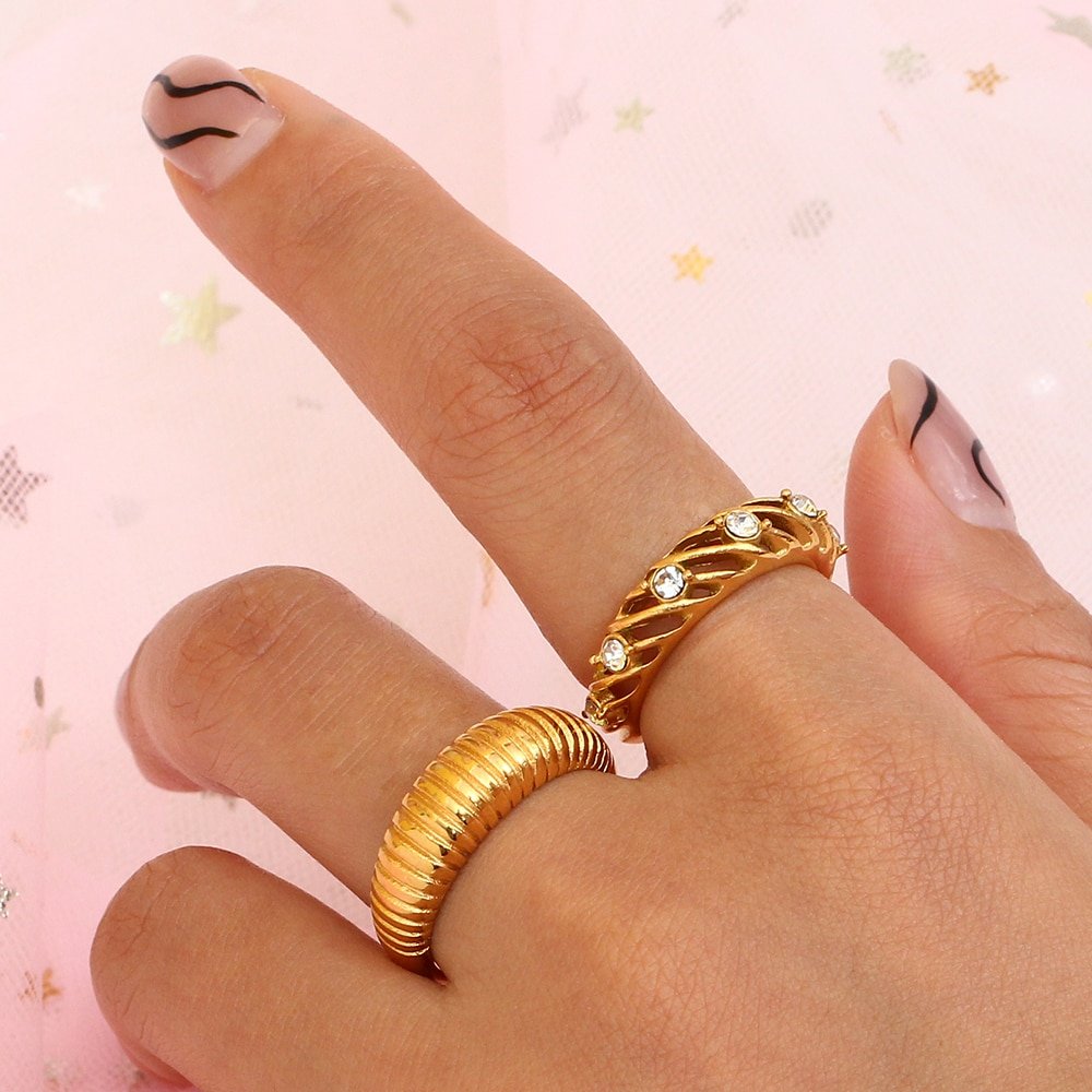 A woman wearing multiple gold statement rings.