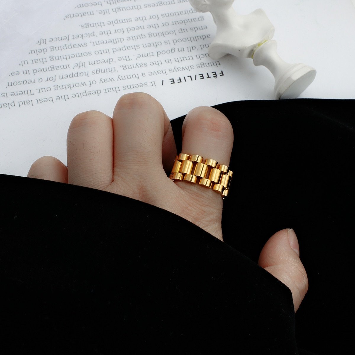 A woman wearing a gold watch link ring band.