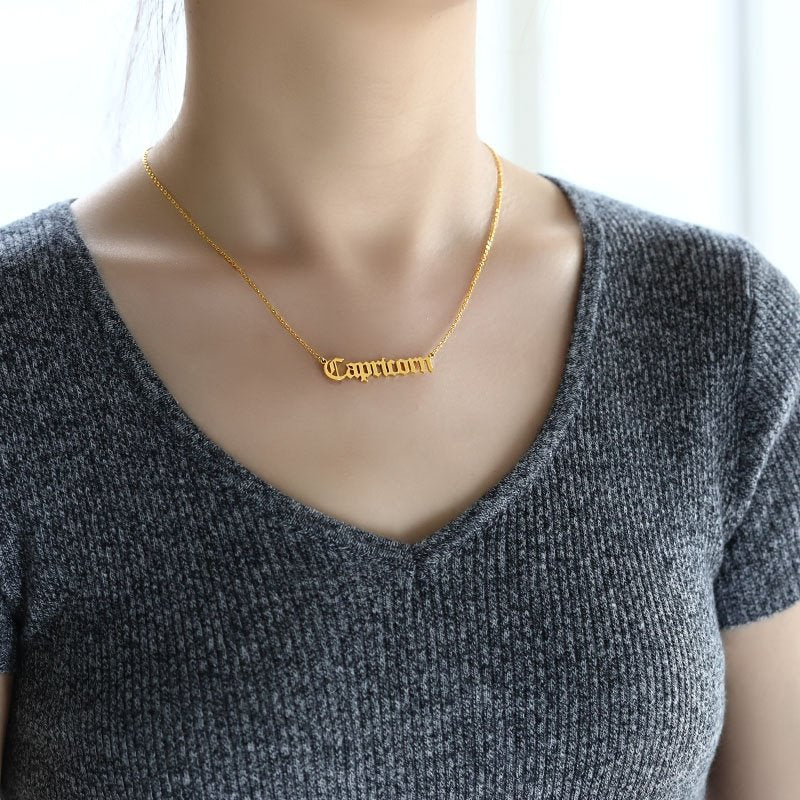 A model wearing a gold Capricorn Name Plate Necklace.