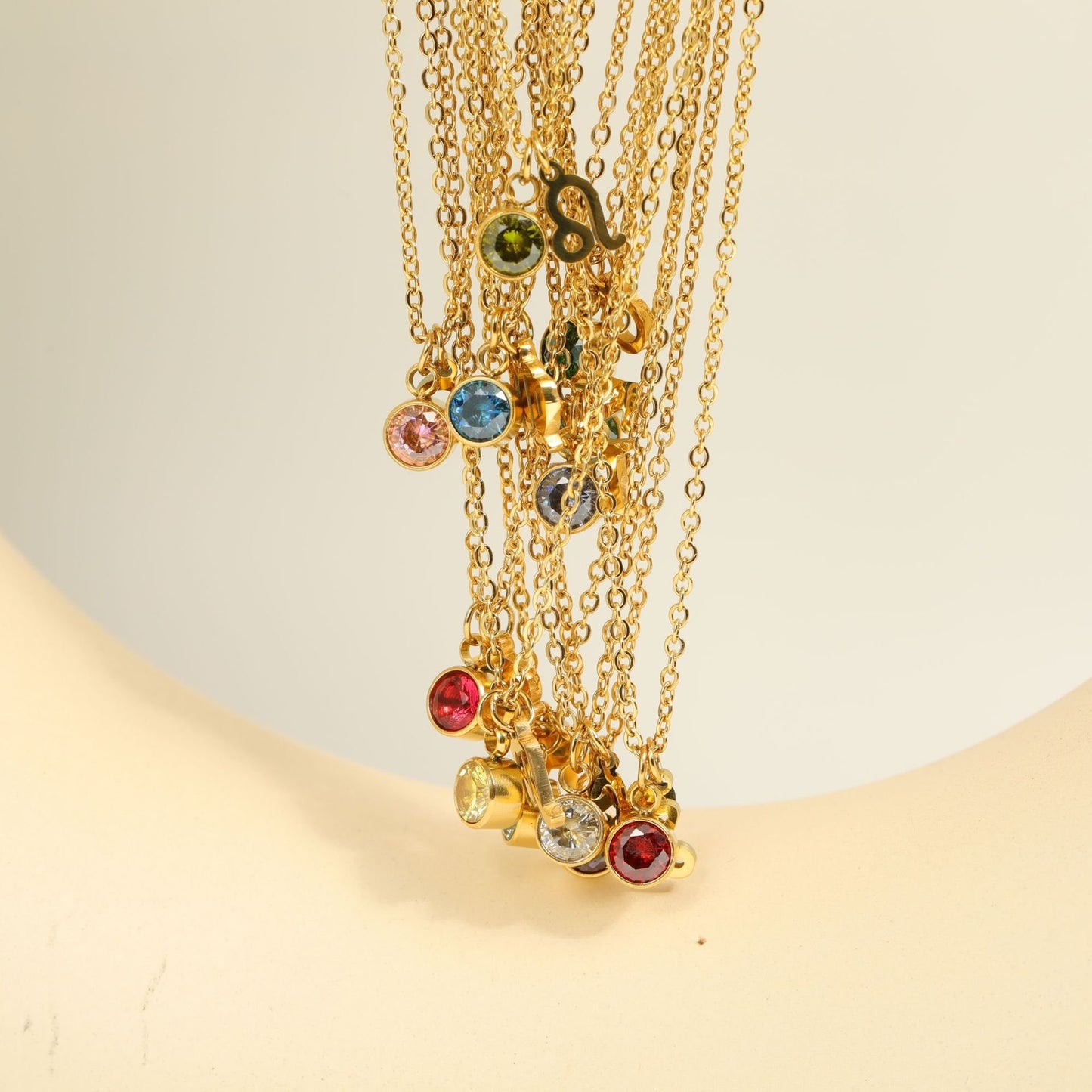 Twelve gold zodiac and birthstone necklaces.