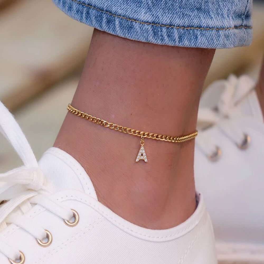 A woman wearing a gold initial anklet.