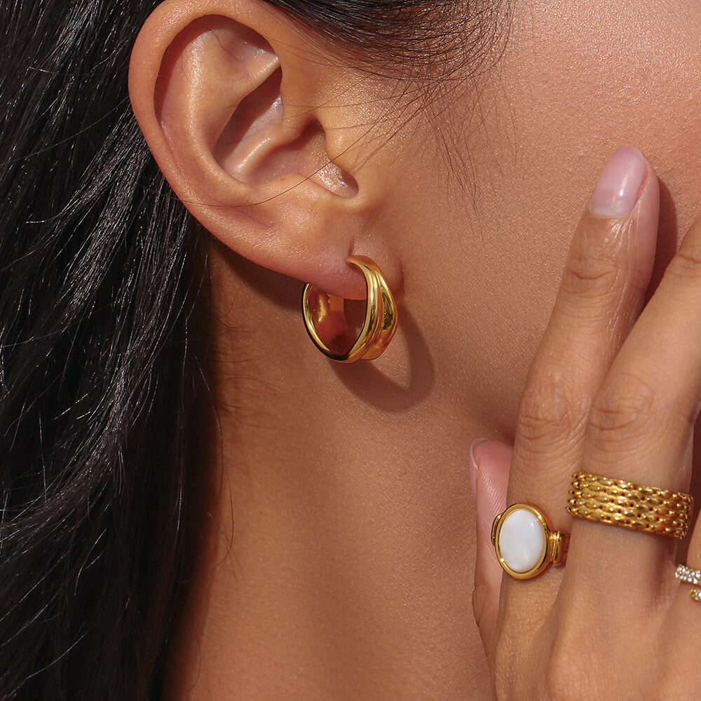 A model wearing organic gold hoops.