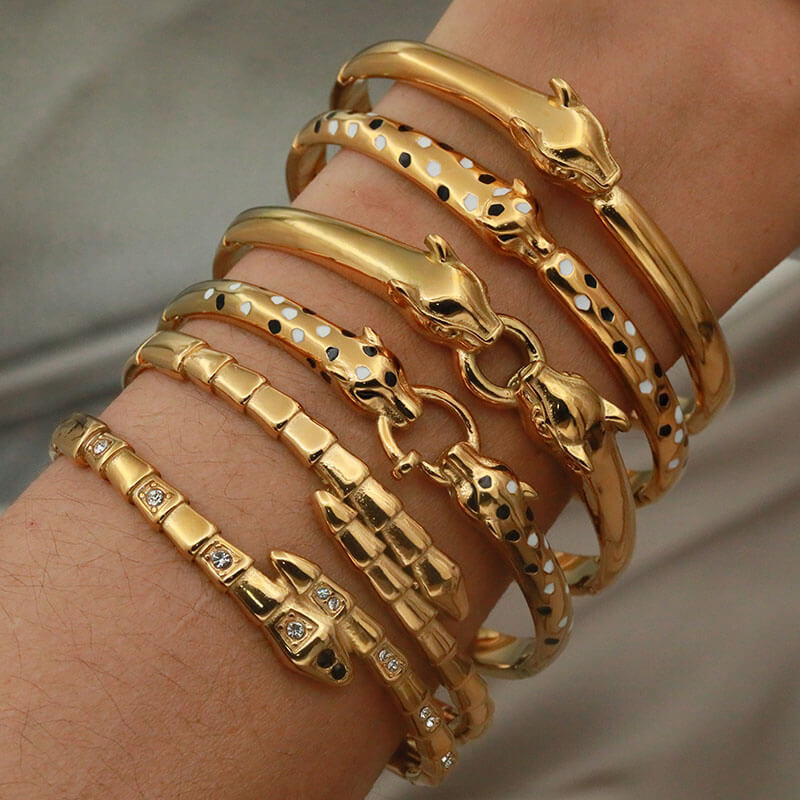 A woman wearing multiple gold leopard and snake bangles.