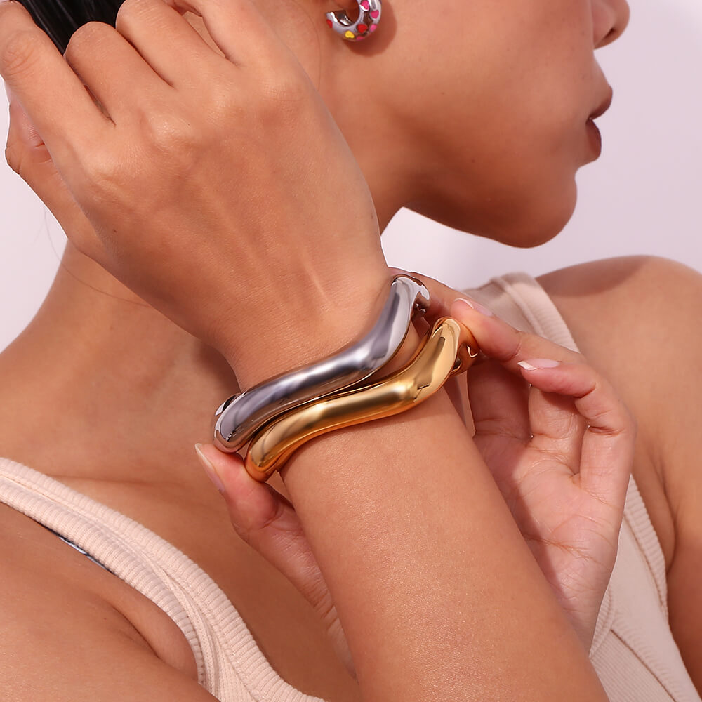 A model wearing chunky gold and silver bracelets.