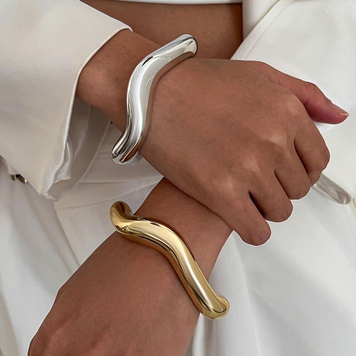 A model wearing silver and gold Wavey Chunky Bangles.