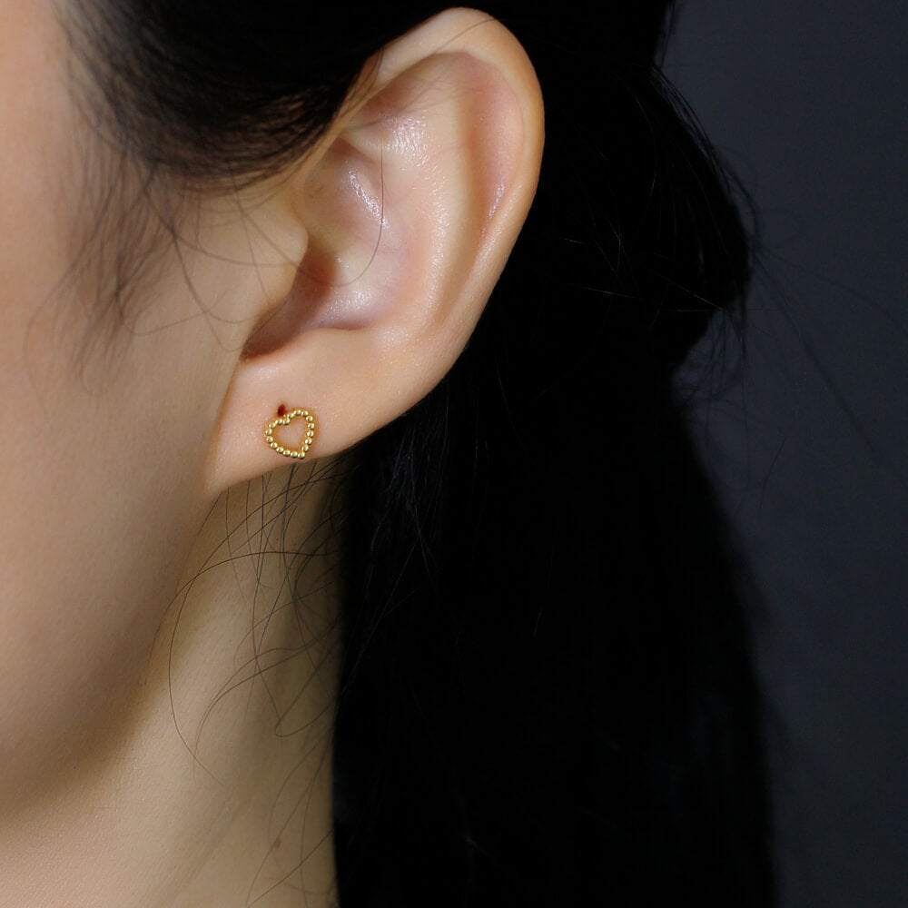 A model wearing the gold Beaded Heart Studs.