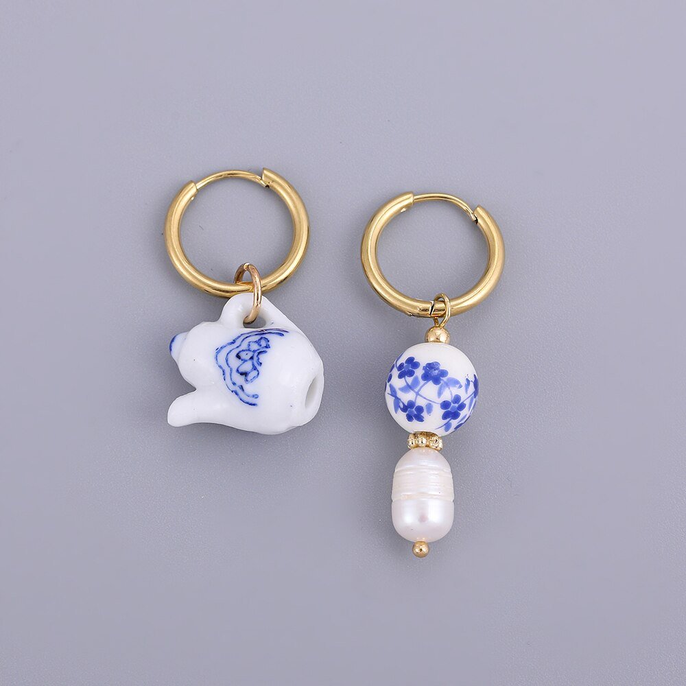 Blue and white ceramic earrings on gold hoops.