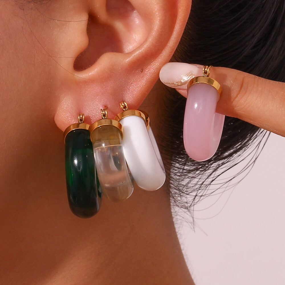 A model wearing multiple chunky colored hoop earrings.