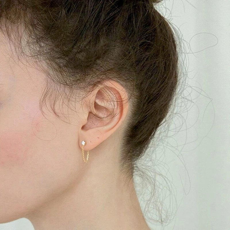A model wearing gold chain earrings.
