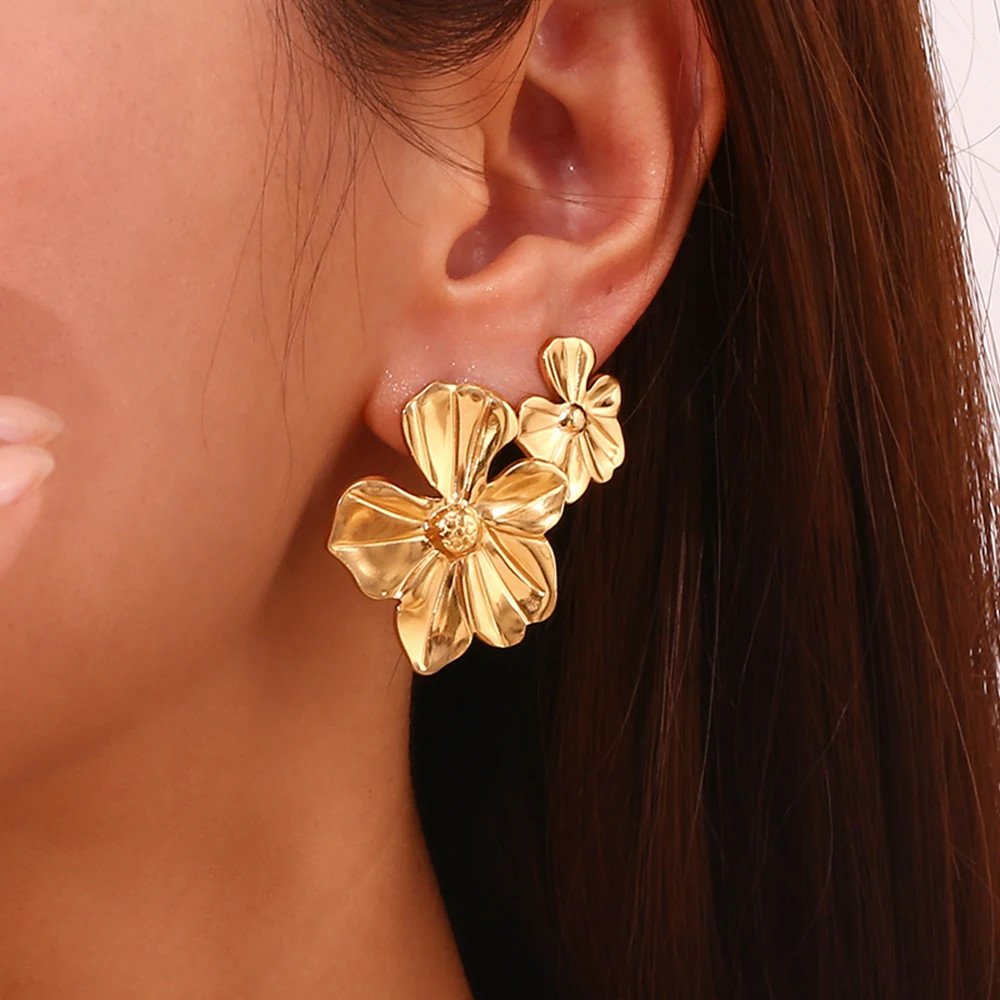 A woman wearing gold Flower Statement Earrings.