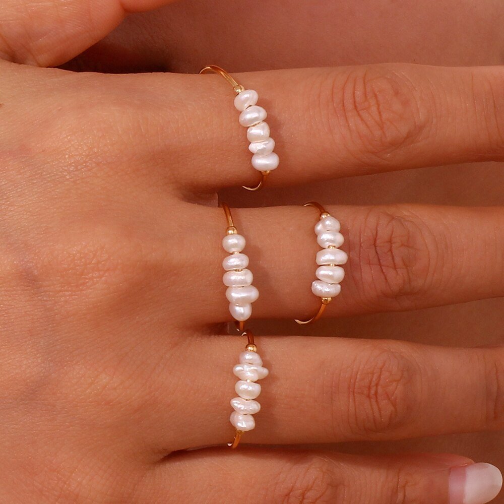 A woman wearing pearl stacking rings.