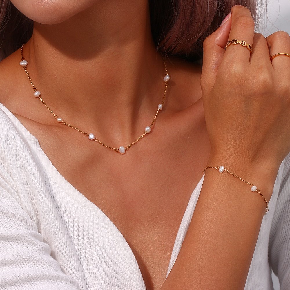 A woman wearing a gold and pearl necklace.