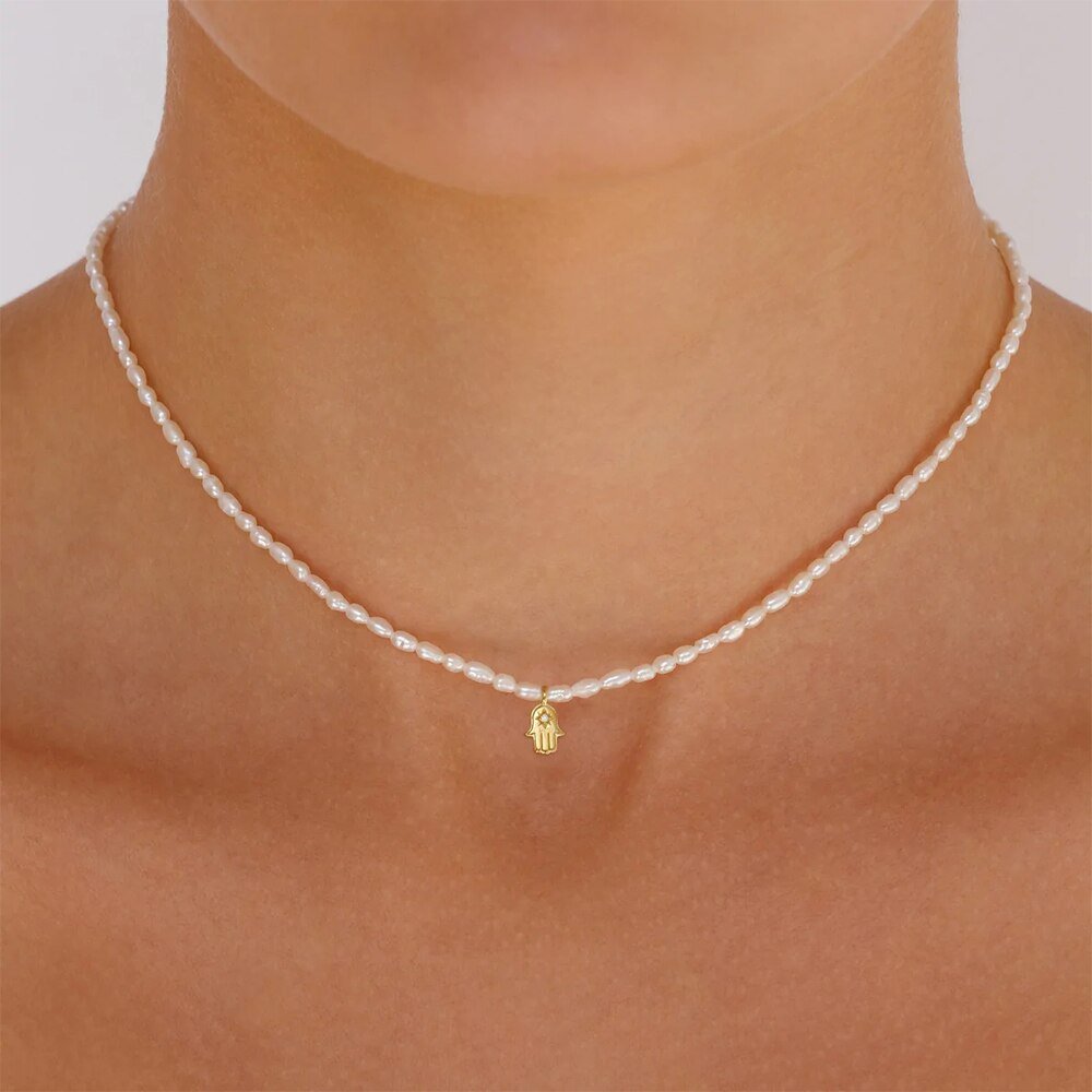 A model wearing a Hamsa Hand Pearl Charm Gold Necklace.