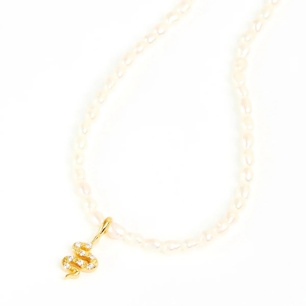 Gold snake pendant strung on a pearl necklace.