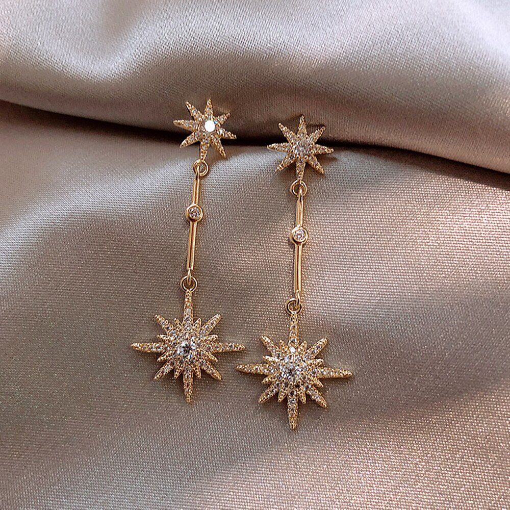 Closeup of the Sparkling Star Gold Dangle Earrings.