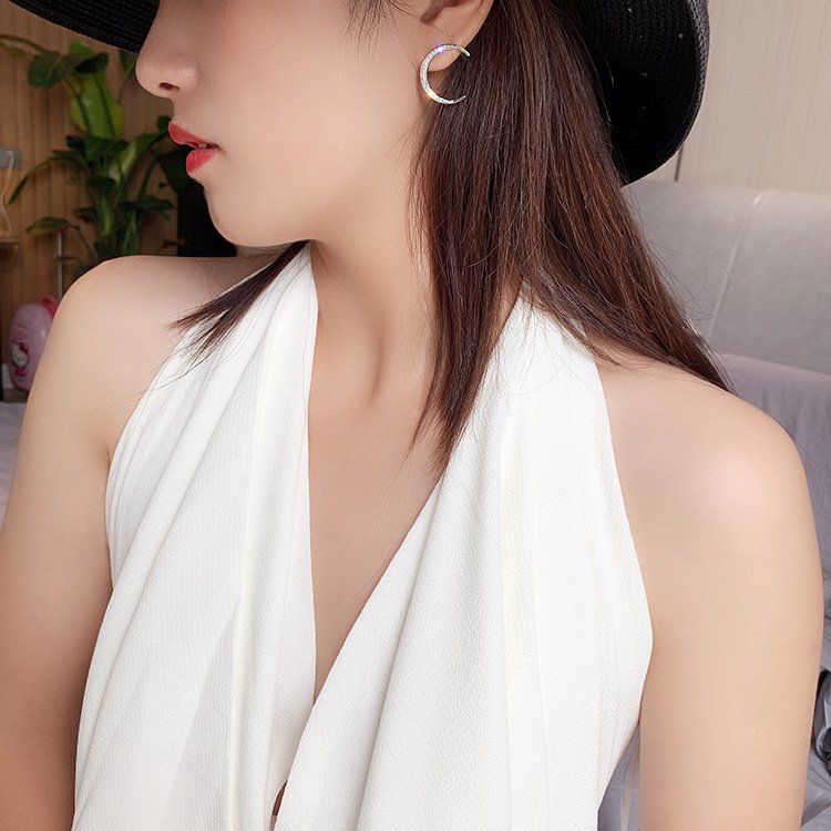 A woman wearing sparkly CZ crescent moon earrings.