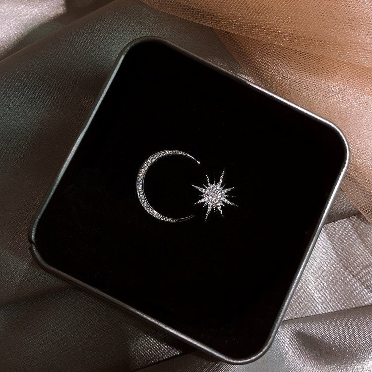 Asymmetrical Star Moon Earrings in a black box.