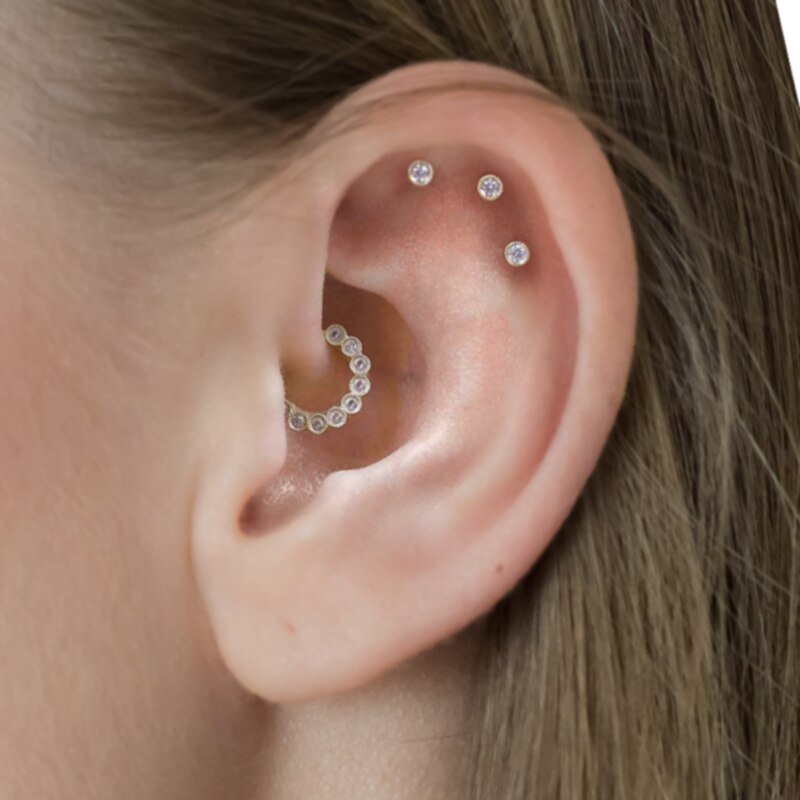 A woman modeling the Bastet CZ Daith Piercing along with other cartilage piercings.